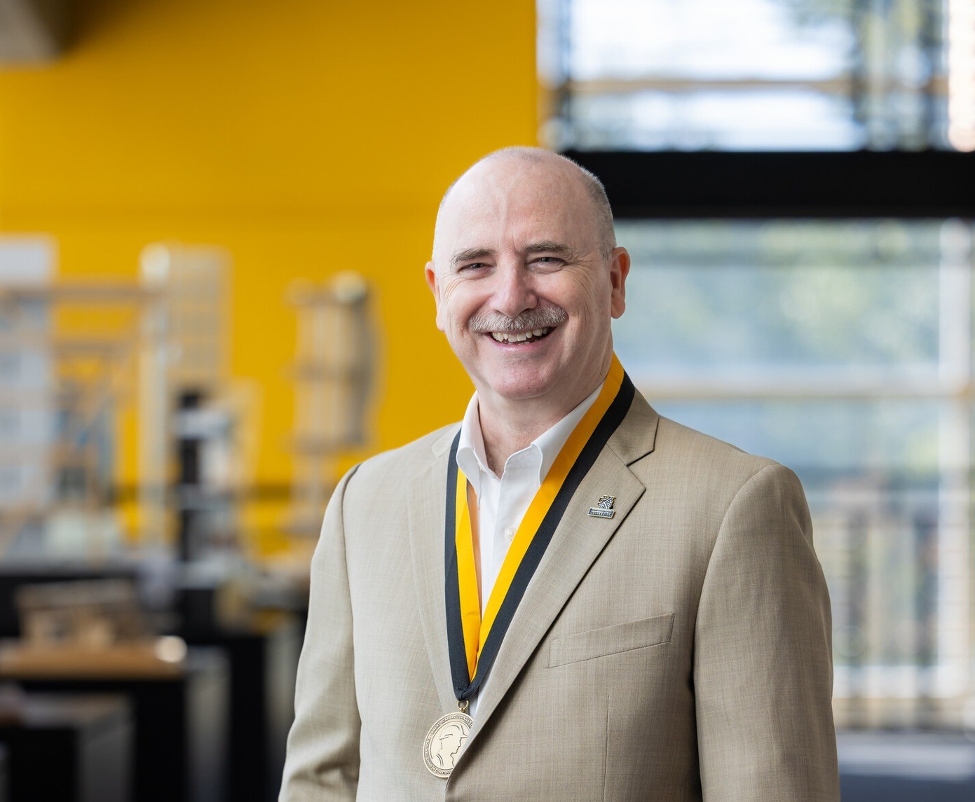 Professor Brian Moore smiling as he stands in the lobby of the architecture building.