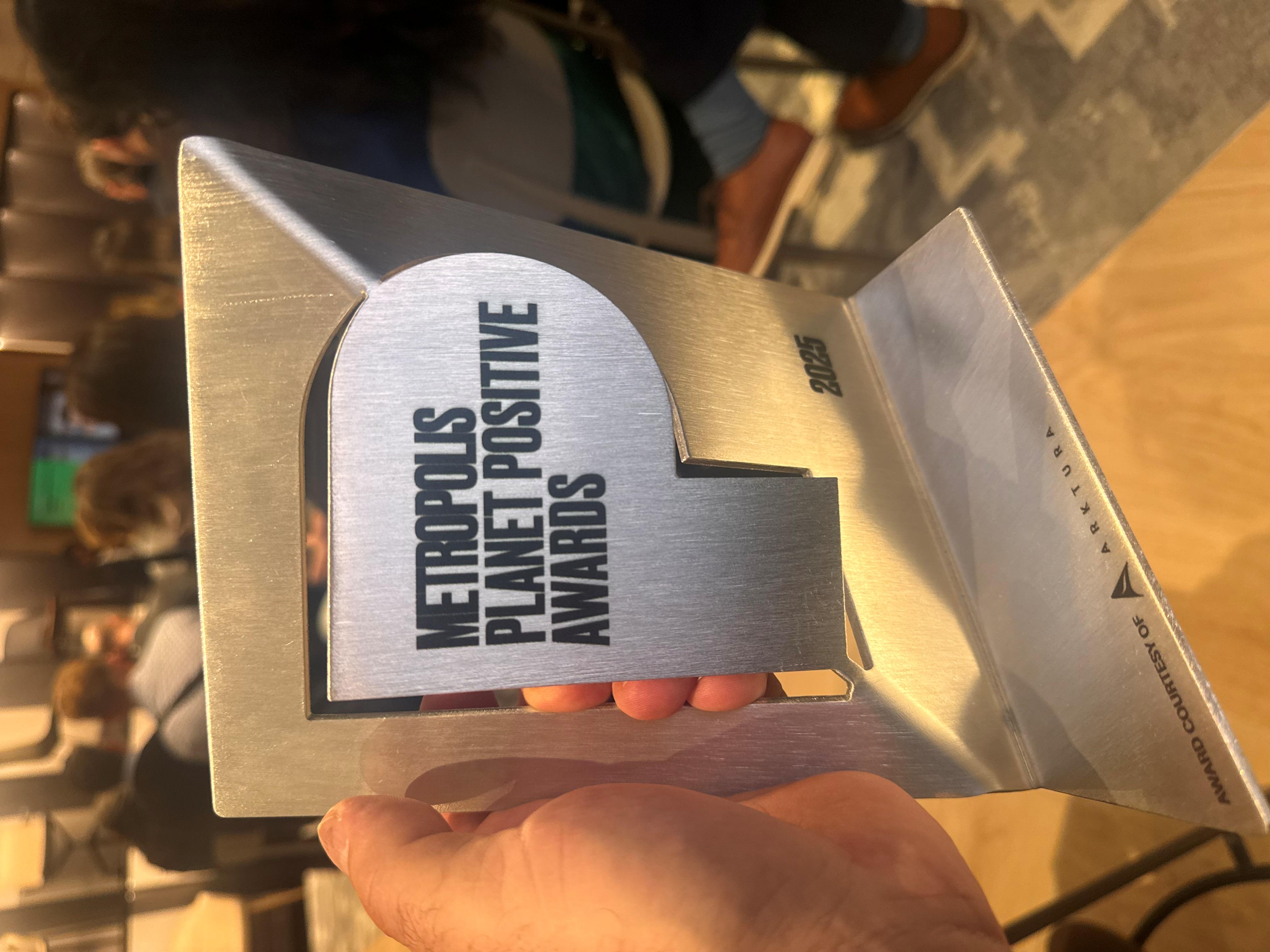 Metal award reading "Metropolis Planet Positive Awards."