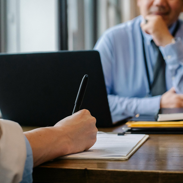 human resource rep writing on document behind computer while doing background check