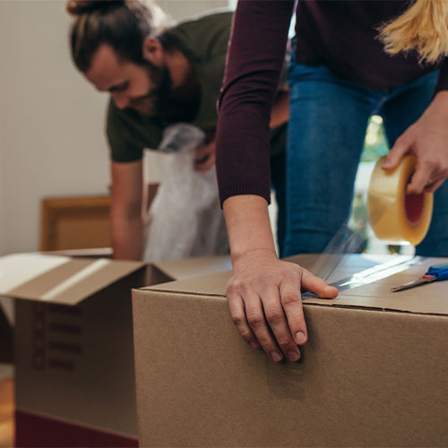 woman and man taping up boxes.
