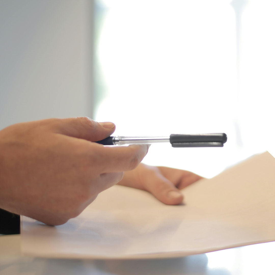 close up on man's hand writing policy with pen on paper