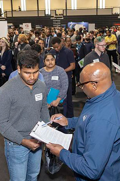 people lined up to talk to recruiter at job fair