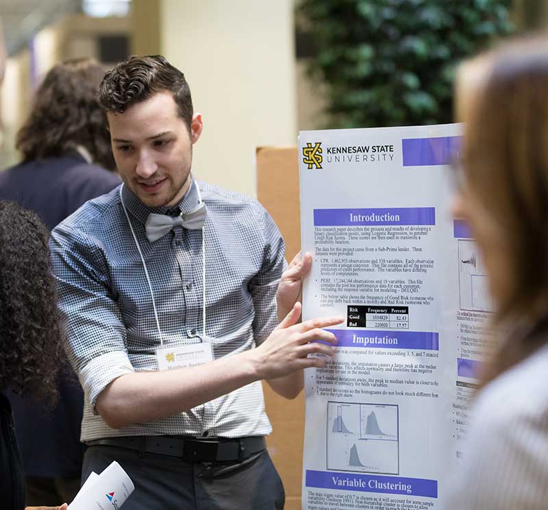 Data Science student explaining his research at a networking event.