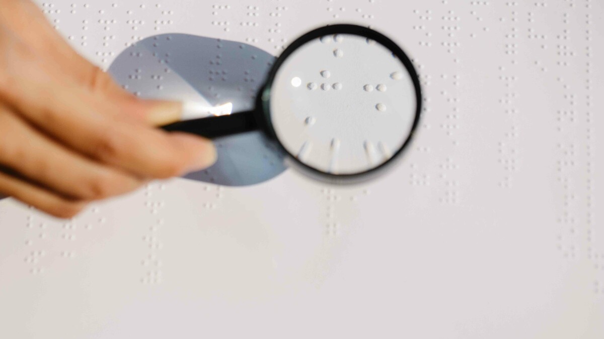 person reading brail with a magnifying glass