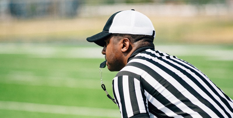 A football referee in a white cap.