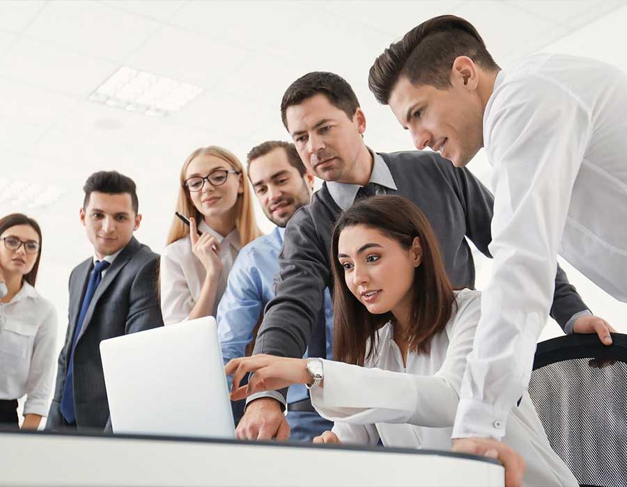 group of people surrounding a laptop communicating.