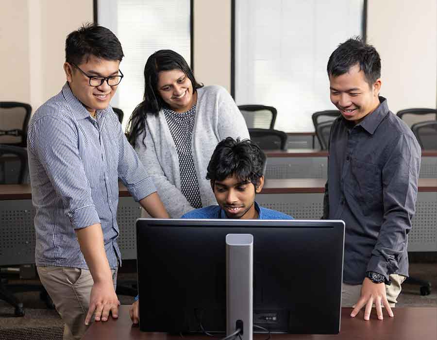 group of ccse students gathered around a computer.