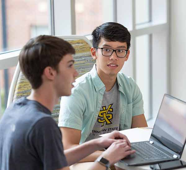 two ksu students working on laptop together