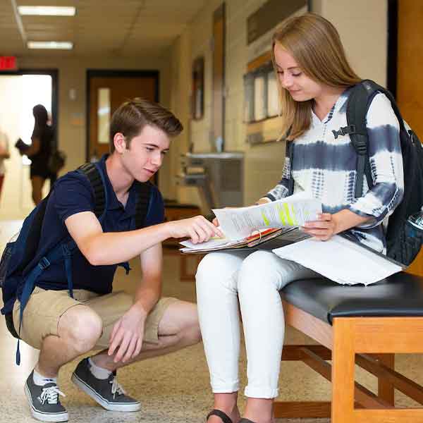 Two undergraduate KSU students looking at class work.