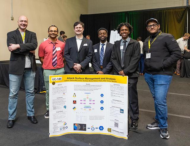 A picture of the first place winners for Undergraduate Capstone project, UC-144 Attack Surface Management and Analysis by Danard S McLemore, Nick A Tanner, Keshaun Berry, Nelson Thairu, and Niang Ciin
