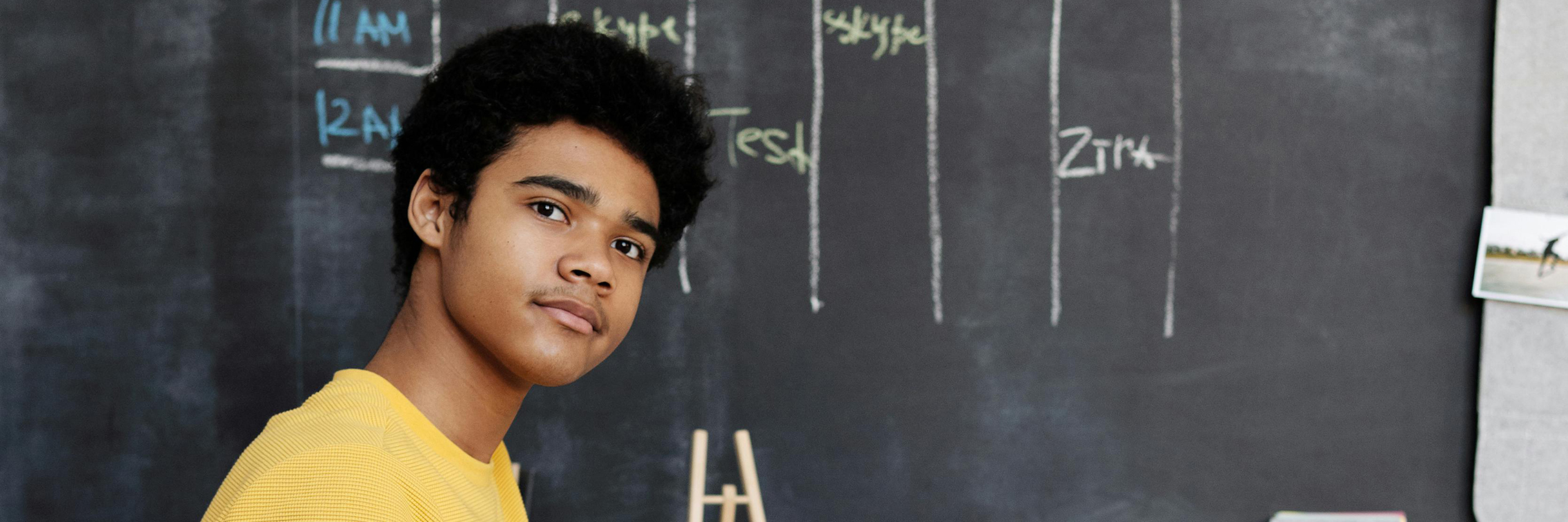 A young man, his gaze hopeful, looks straight toward camera. 
