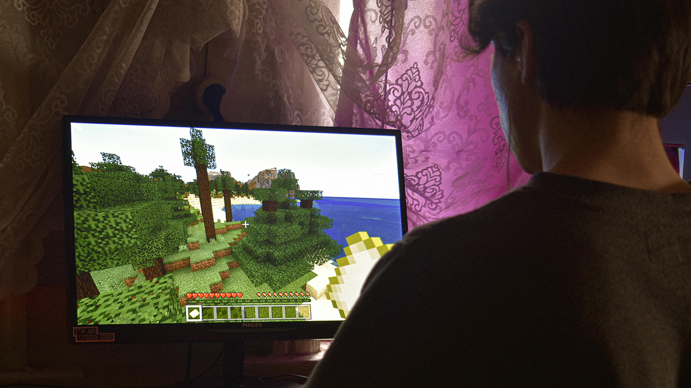 A teenager builds a world in Minecraft.