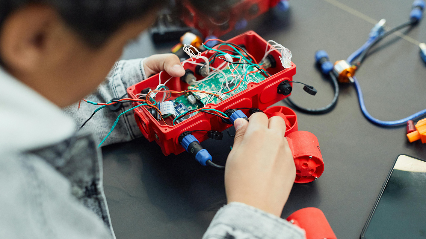 A computer engineering student rewires a robot.