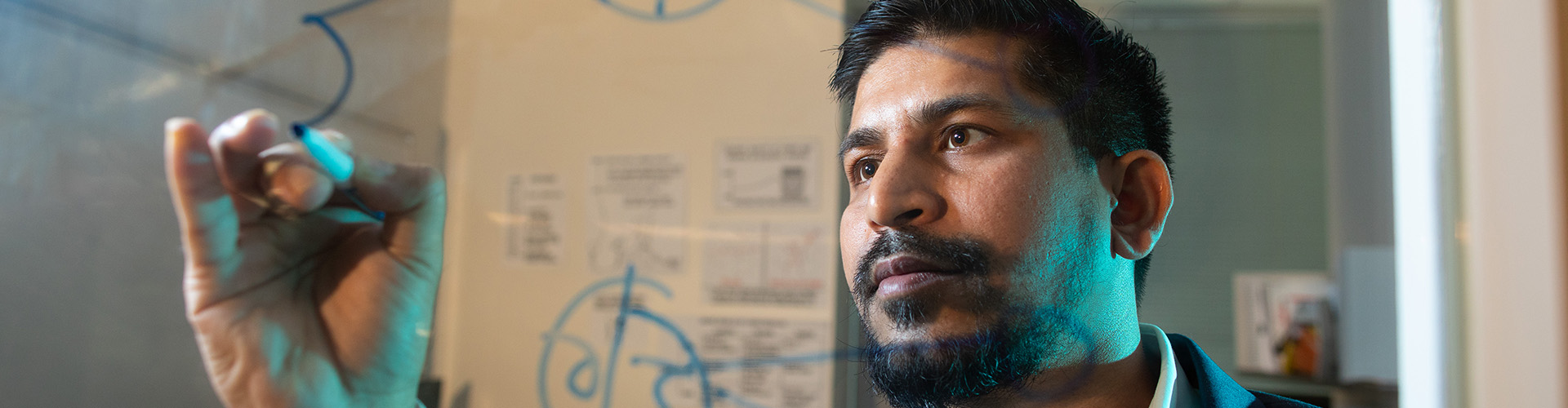 man writing on glass wall with expo marker.