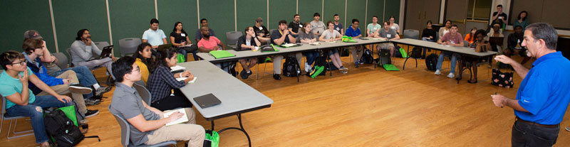 Students sitting at desks, listening attentively at the Hackathon.