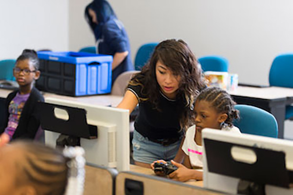 A CCSE student helping out a coding camp attendee.