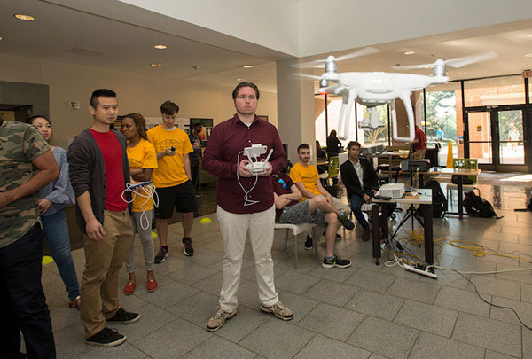 A student piloting a drone with a controller. 