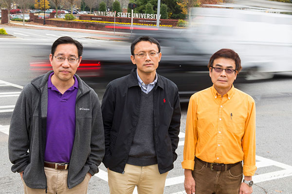 KSU faculty in front of moving cars. 