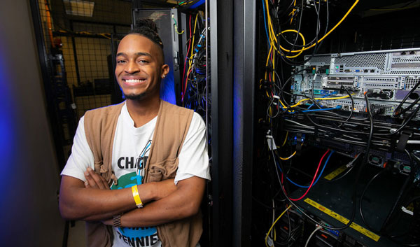 Daniel Omuto posing in front of network cables. 