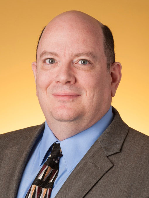 Michael Whitman headshot over a gold background.