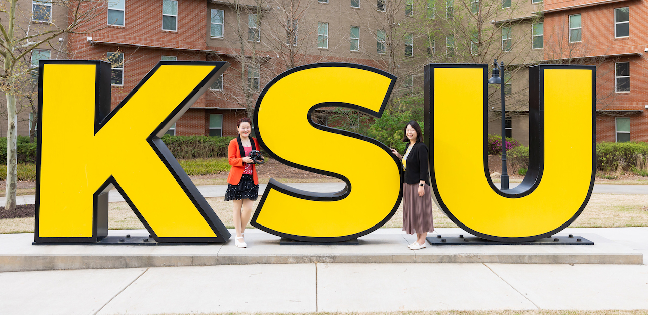 two ccse students sgtanding in outside in front of ksu marietta campus sign