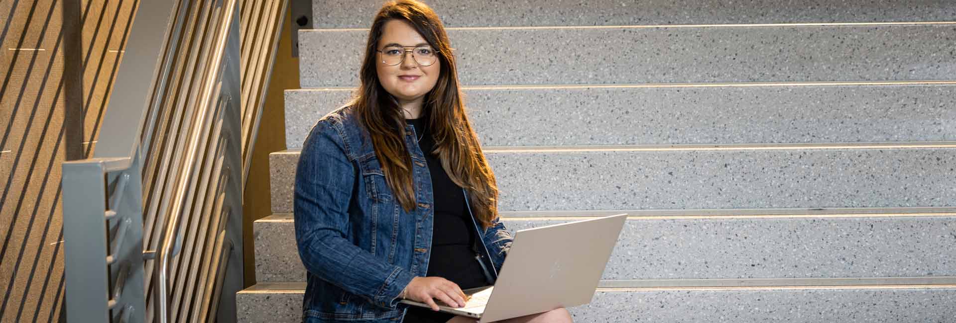 ksu student sitting on stairs with laptop