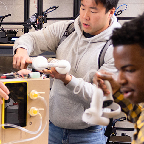 2 male students in the mad lab holding equipment