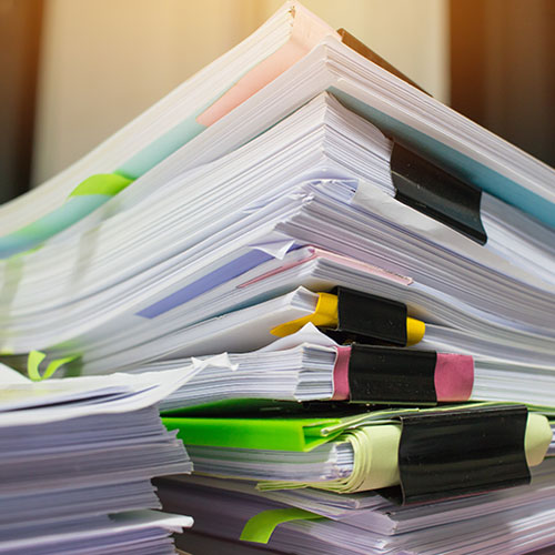 A stack of papers topped with colorful sticky notes, indicating important reminders or tasks.