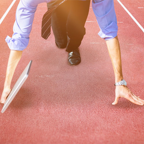 Businessman running on a track while using a laptop, symbolizing self-directed learning and multitasking in a dynamic environment.