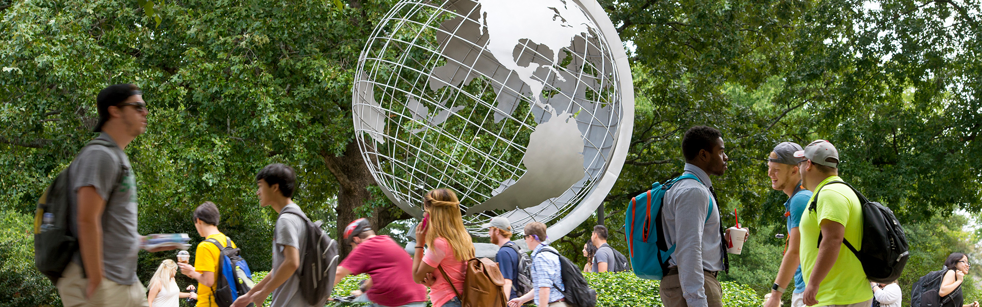 group of students outside in front of a globe monument
