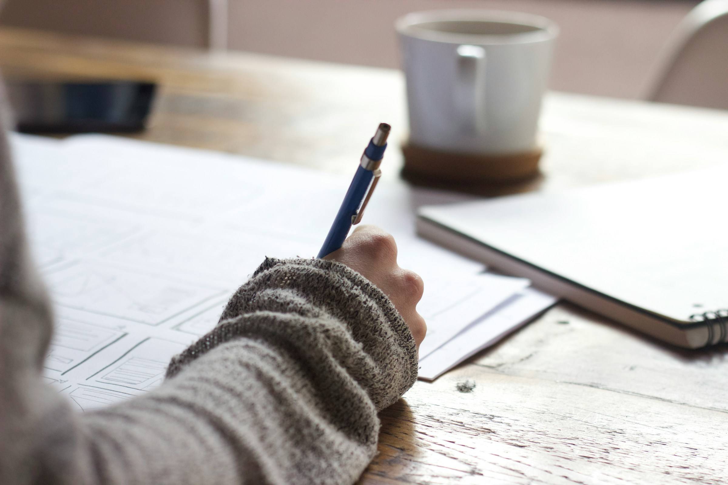 close up of someone doing work at desk with coffee cup