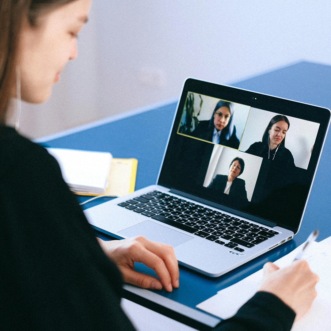 woman working remotely looking at coworkers on virtual meeting