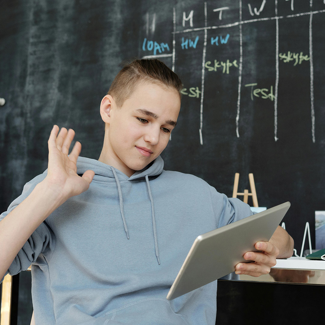 kid looking at tablet in classroom in front of chalkboard