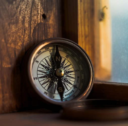 an open compass propped up on a wooden surface signifying a guide