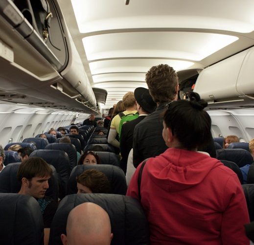 image of people going down the aisle on an airplane. This image signifies onboarding.