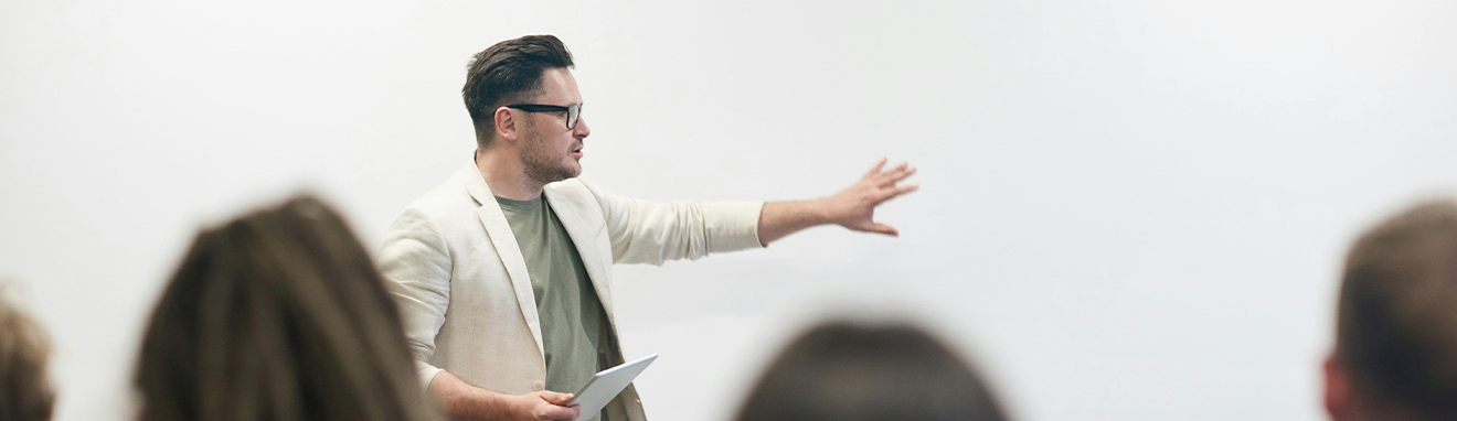 male teacher with arm stretched out teaching to class