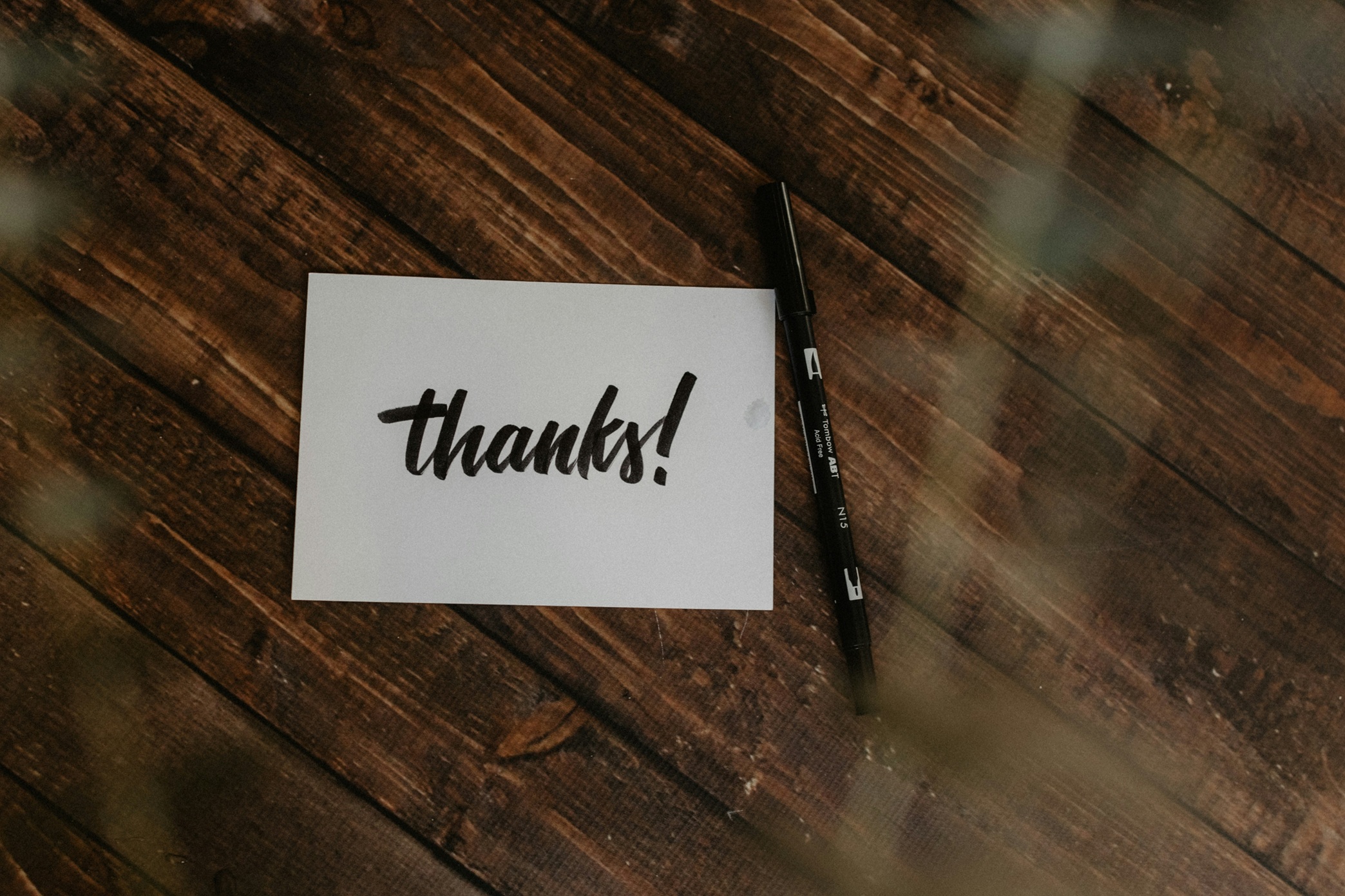 image of a thank you card that says thanks on a wooden surface with a pen