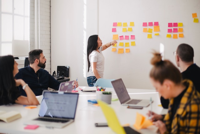 person pointing at white board covered in sticky notes during a training 