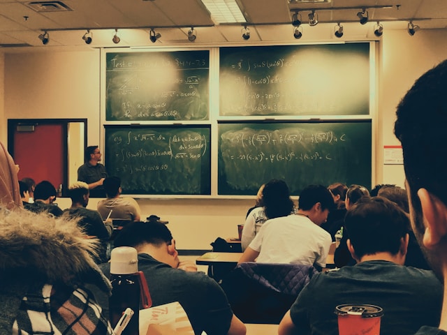 classroom being observed with large chalkboard covered in equations 