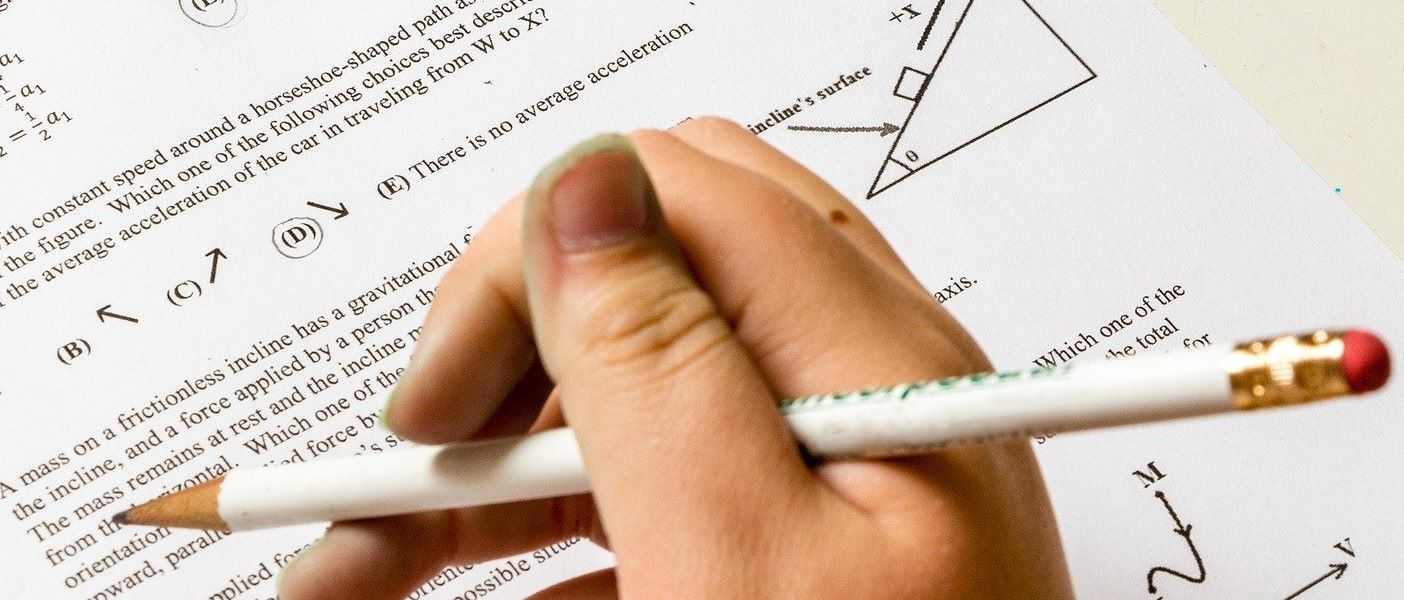 Student holding a pencil over a multiple-choice exam