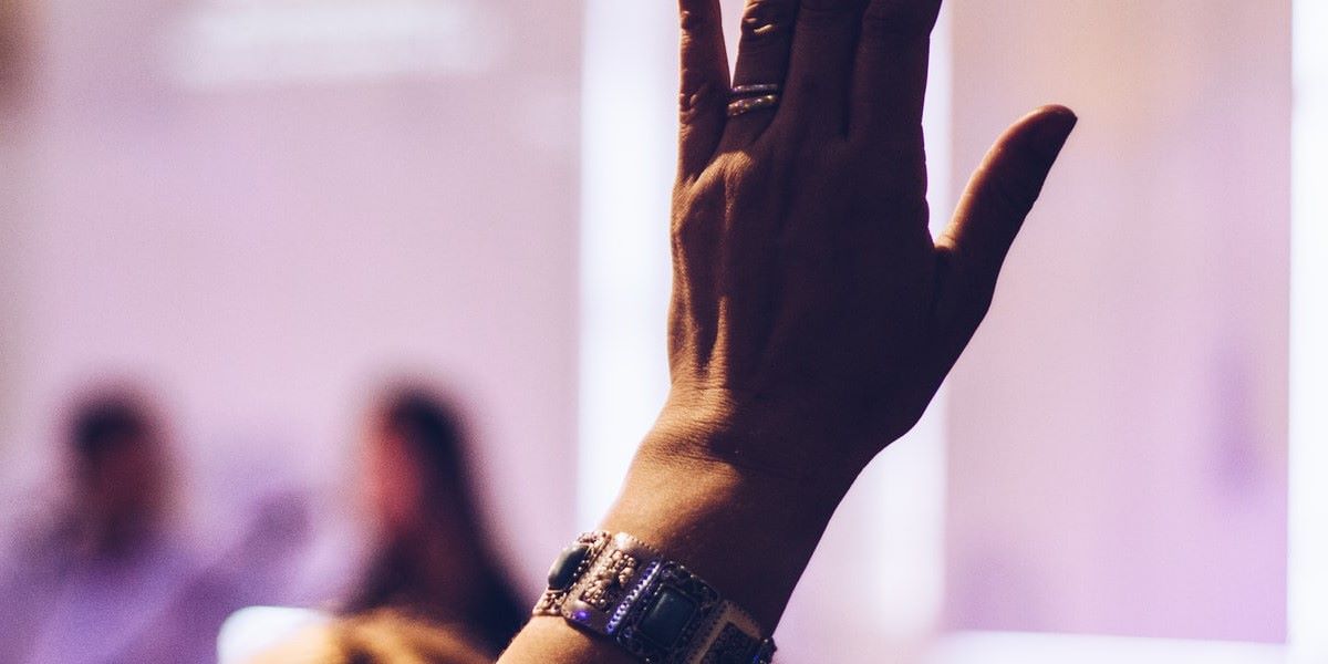 A raised hand in a classroom or meeting setting