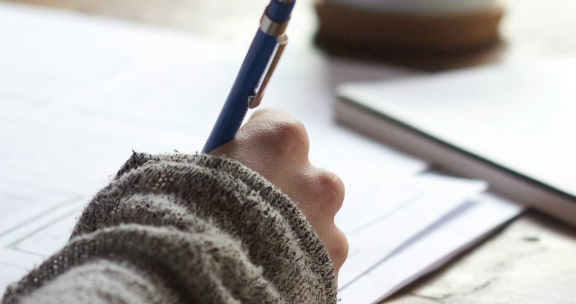 Person holding a pen, writing.