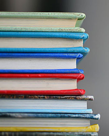Stack of colorful hardcover books viewed from the side, with visible spines and pages.