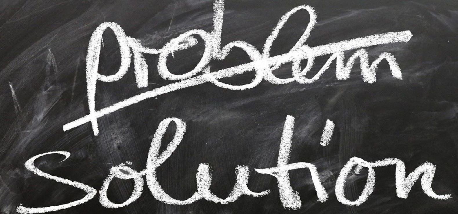 Chalkboard with the word "problem" crossed out and "solution" written below