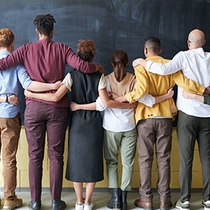 A group of people stands in front of a blackboard discussing Organizational Effectiveness and Leadership strategies.