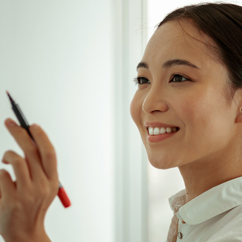 A woman grasping a pen, ready to take notes, showcasing concentration and intent.