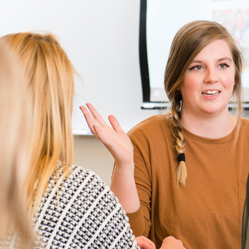 A woman communicates with a group, fostering discussion and interaction among participants.