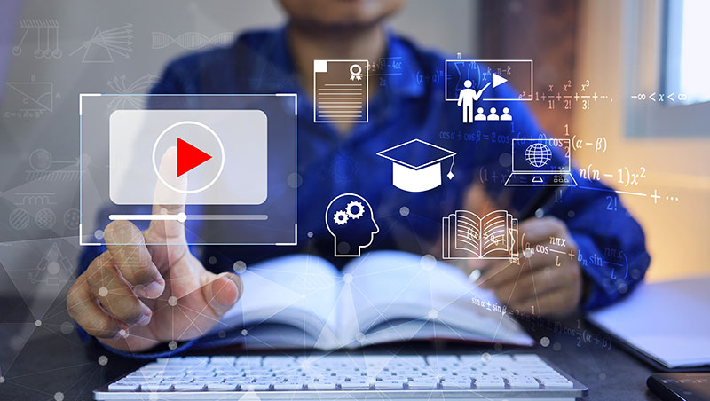A person interacting with a laptop that features a video icon, highlighting online course design..