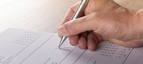 An individual is engaged in writing on paper with a pen, demonstrating concentration and creativity.