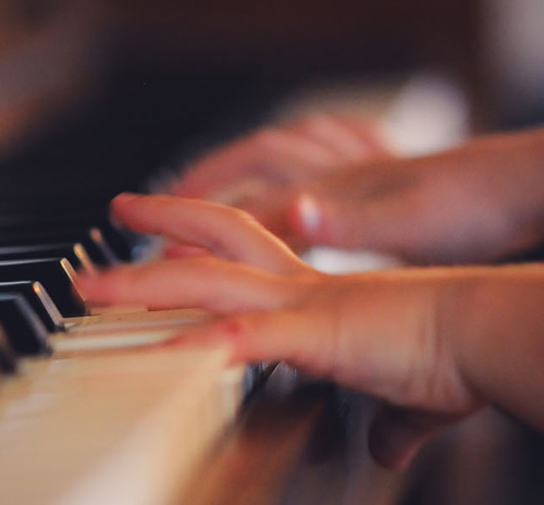 A child's hands skillfully playing the piano, showcasing practice and feedback in music learning.